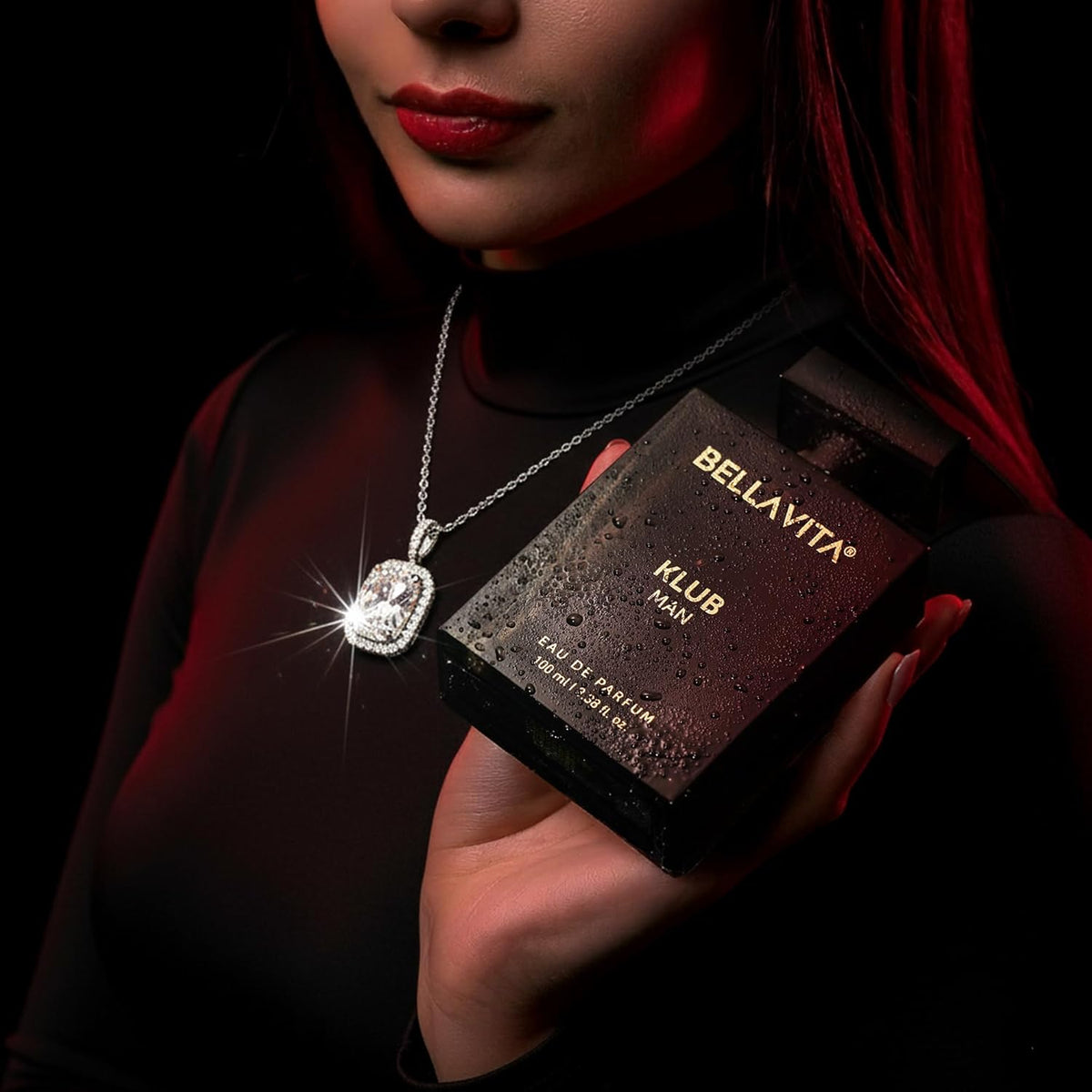 Person holding a Bella Vita Klub Man perfume box with a necklace in the foreground