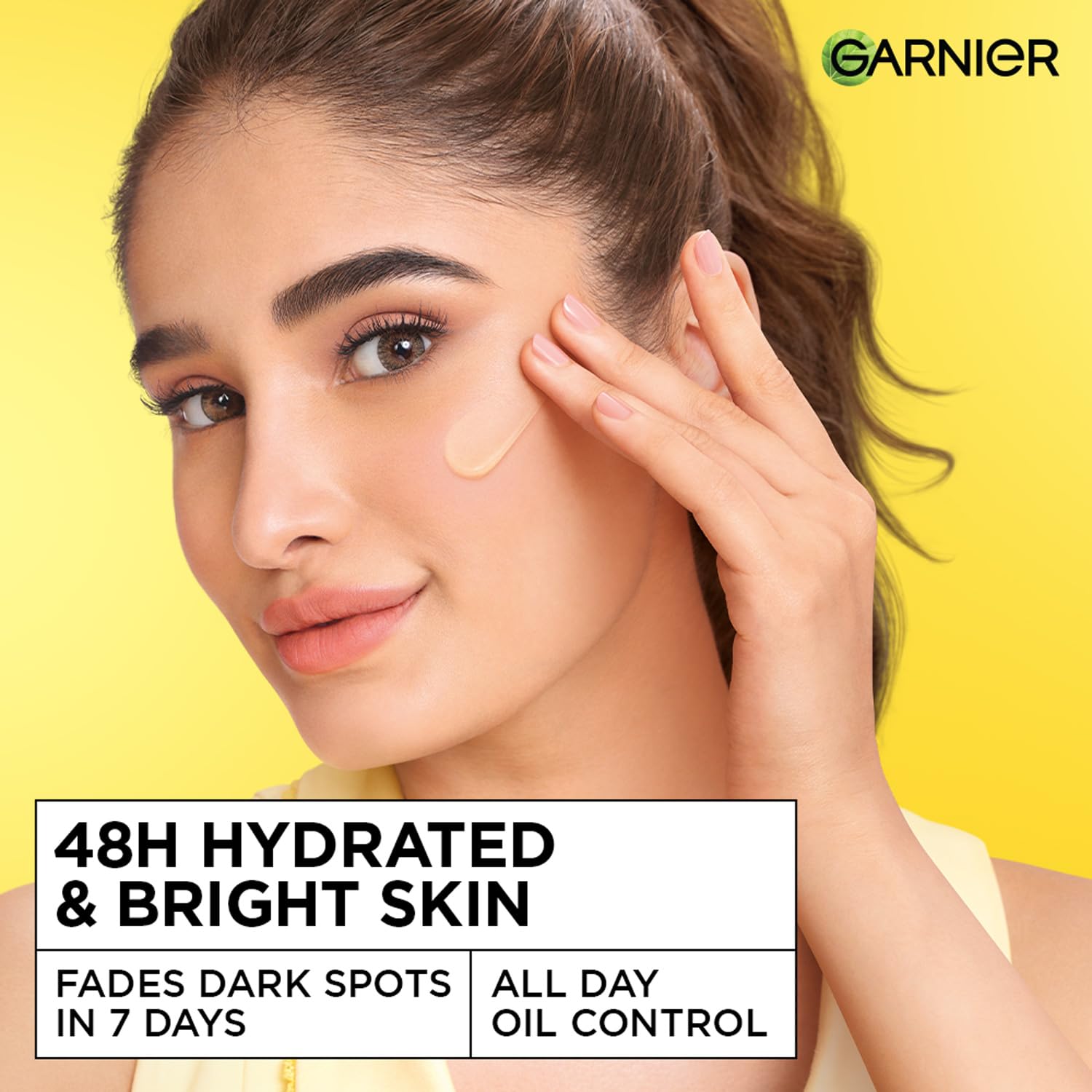 Woman applying skincare product with Garnier logo on a yellow background
