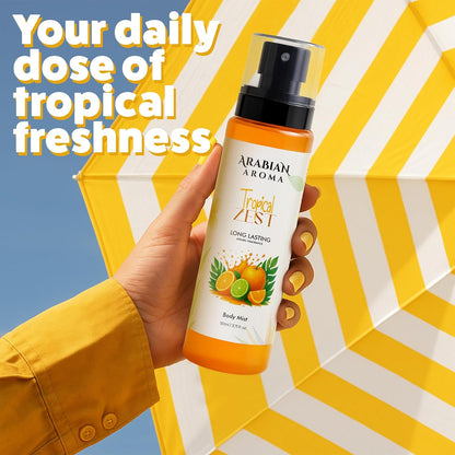 Hand holding a bottle of Arabian Aroma Tropical Zest body mist against a yellow and white striped background.