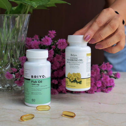 Two bottles of Briyo Fish Oil and Evening Primrose Oil on a table with flowers in the background.