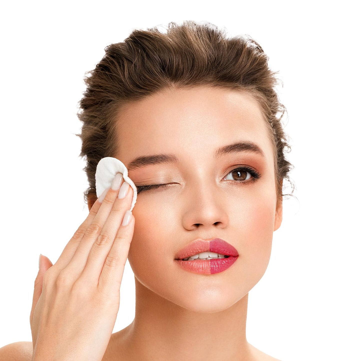 Woman applying a white cotton pad to her face against a white background