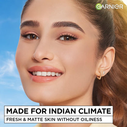 Woman with makeup and earrings against a blue sky, with Garnier branding and text about skin care.