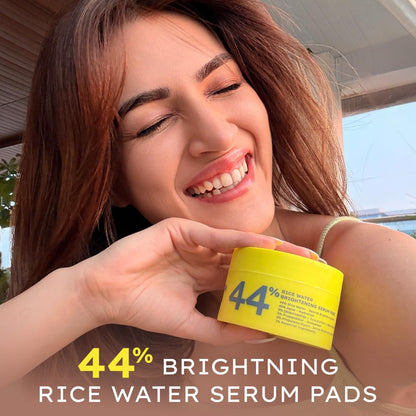 Woman holding a yellow container of 44% Brightening Rice Water Serum Pads with text overlay.