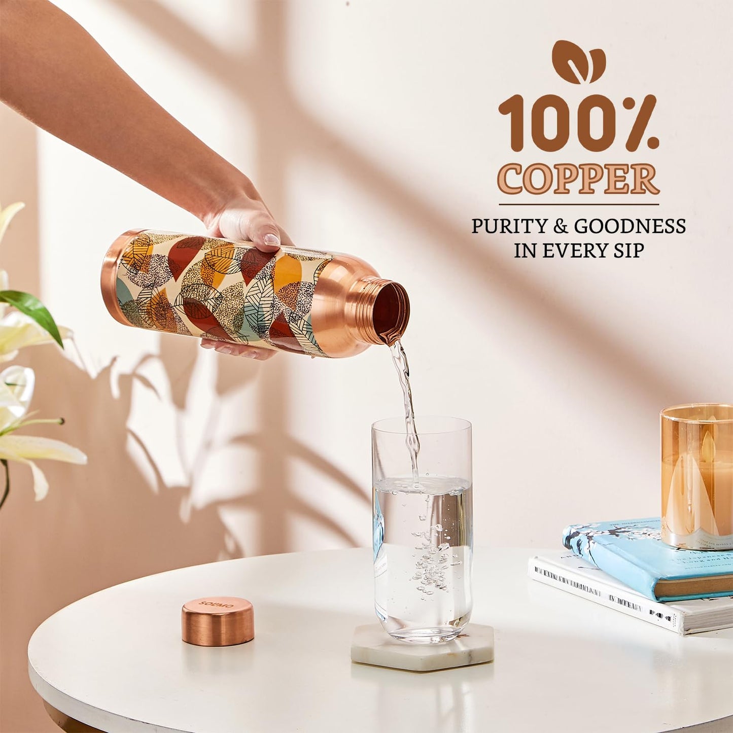 Copper water bottle being poured into a glass with '100% Copper' branding in the background.