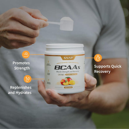 Person holding a container of SNAP BCAAs supplement with text highlighting benefits.