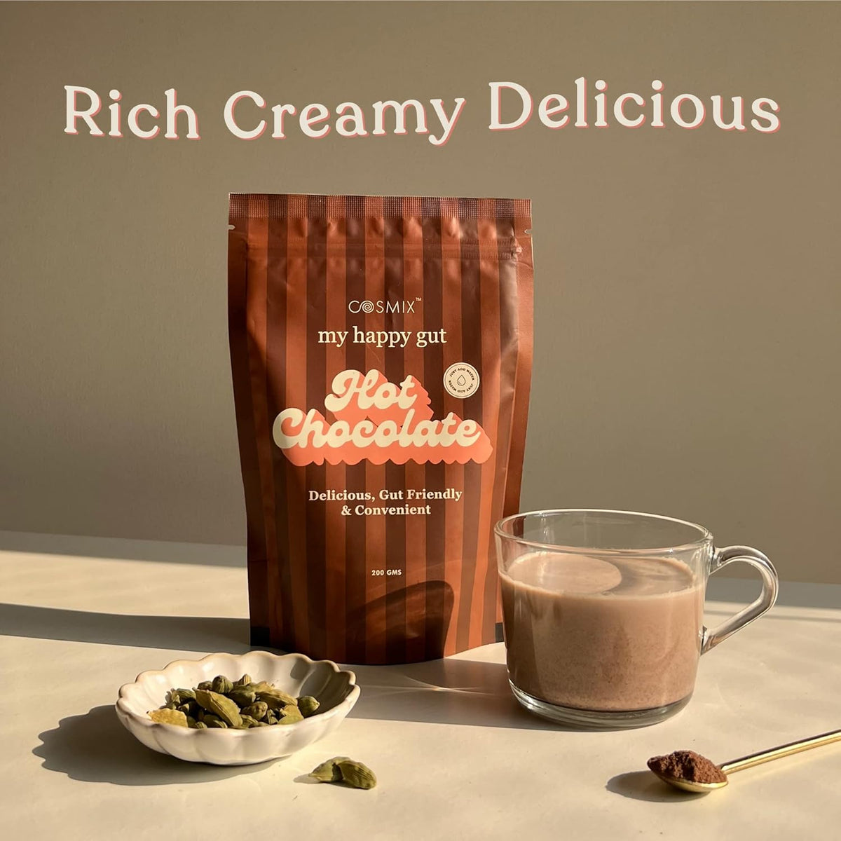 Hot chocolate package with a cup of hot chocolate, green herbs, and a spoon on a neutral background.