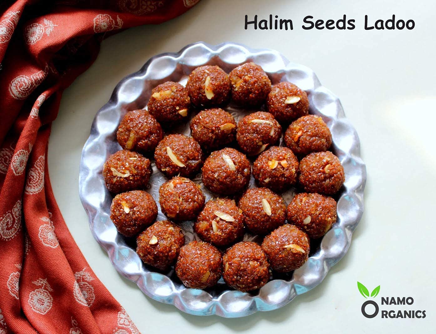 Plate of Halim Seeds Ladoo with a red patterned cloth on a white background, featuring the Namo Organics logo.