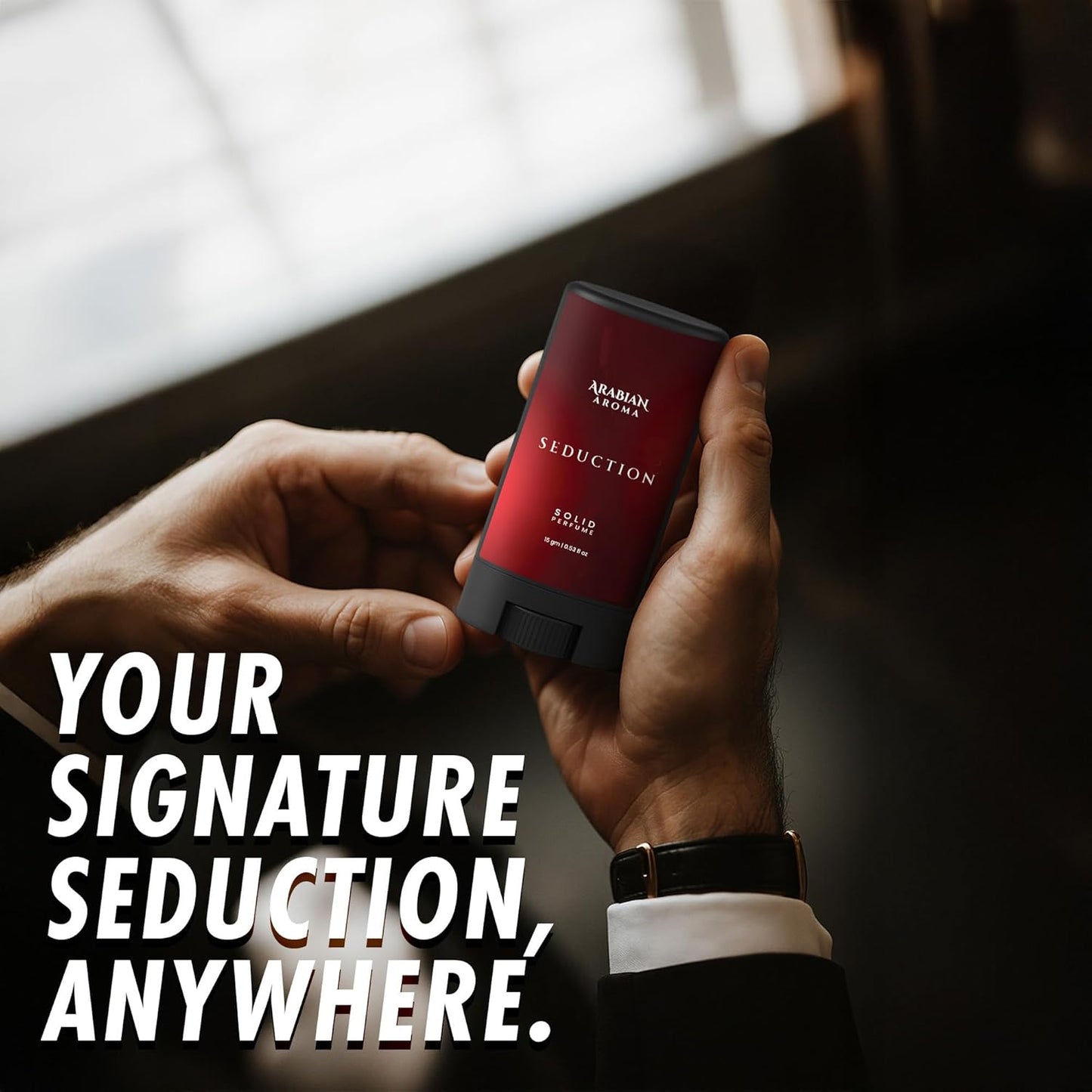 Hand holding a red Arabian Oudh Seduction perfume stick with text overlay.