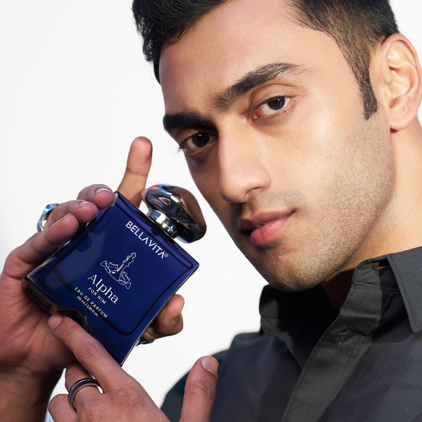 Man holding a blue Bellavita Alpha perfume bottle against a white background