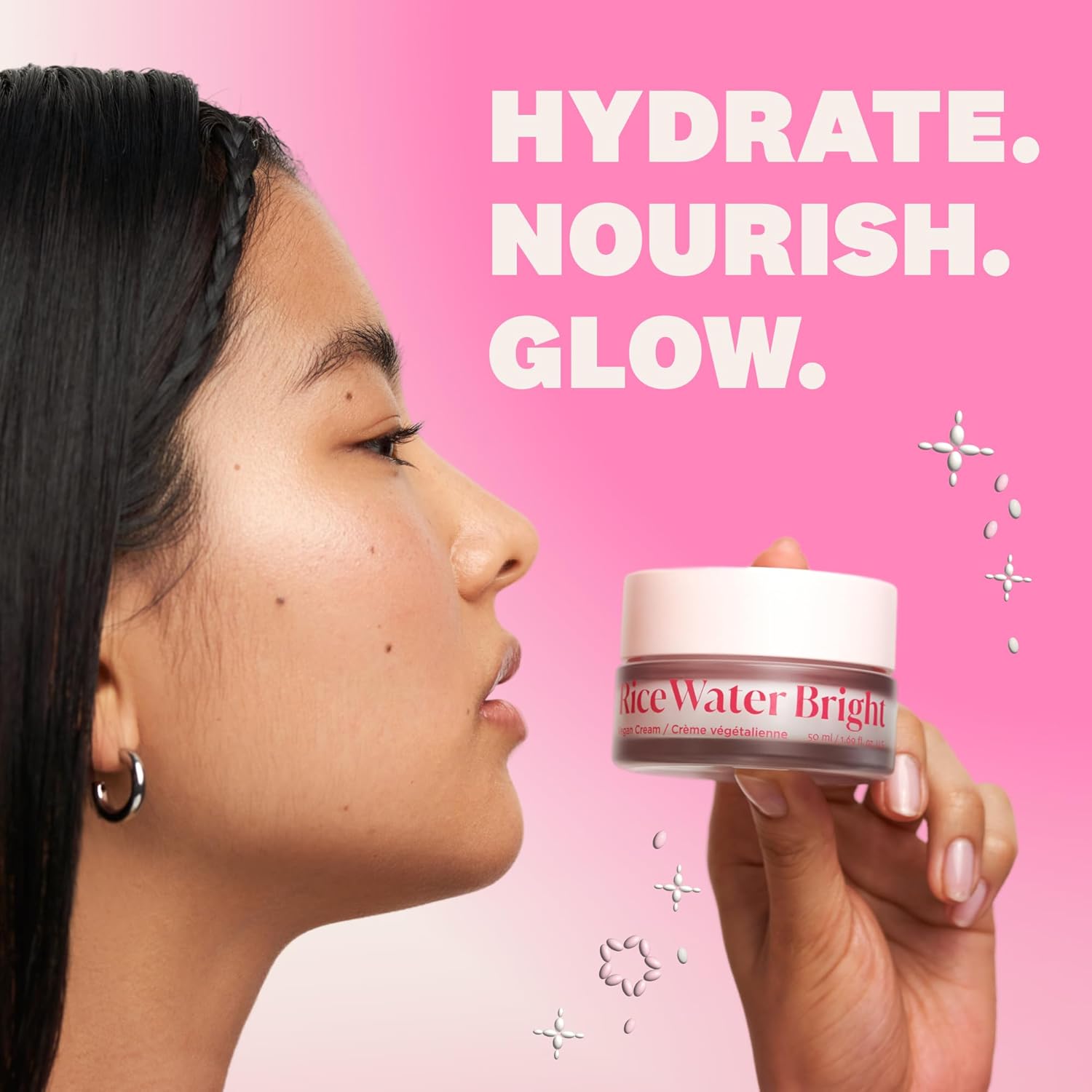 Woman holding a jar of 'Rice Water Bright' cream with text 'HYDRATE. NOURISH. GLOW.' on a pink background