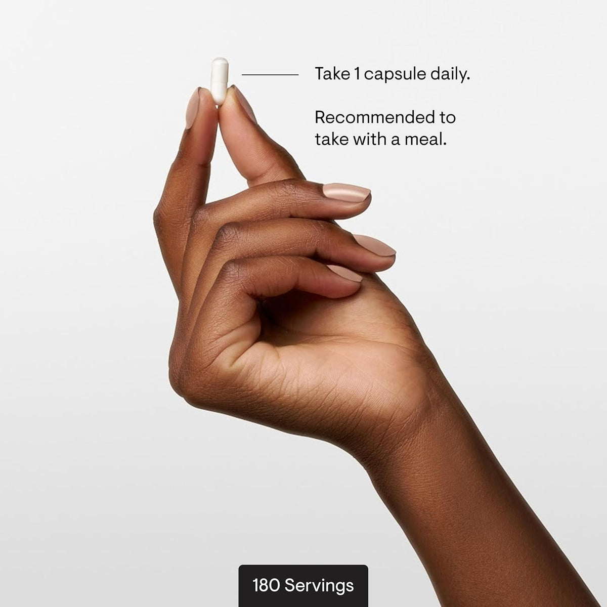 Hand holding a capsule with text on a light gray background
