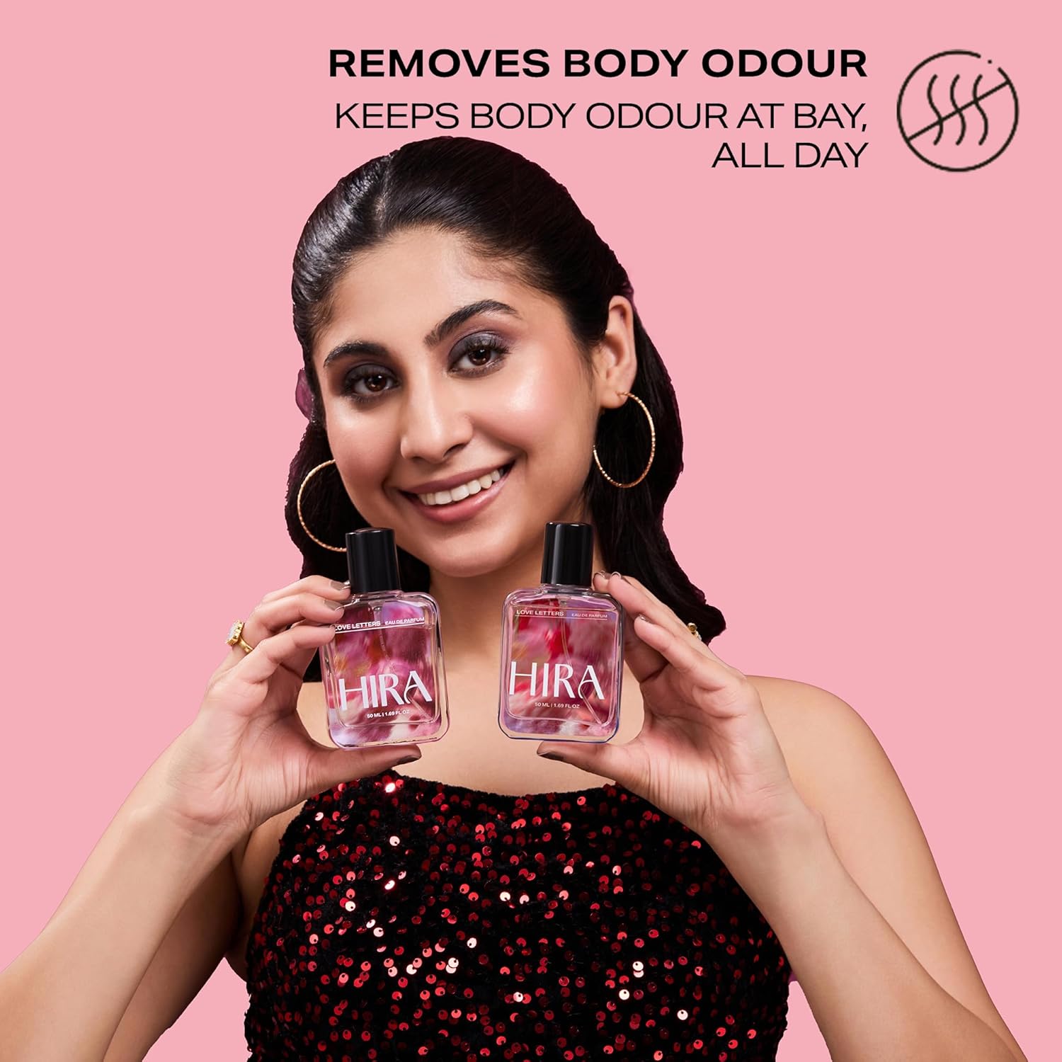 Woman holding two bottles of HIRA product against a pink background
