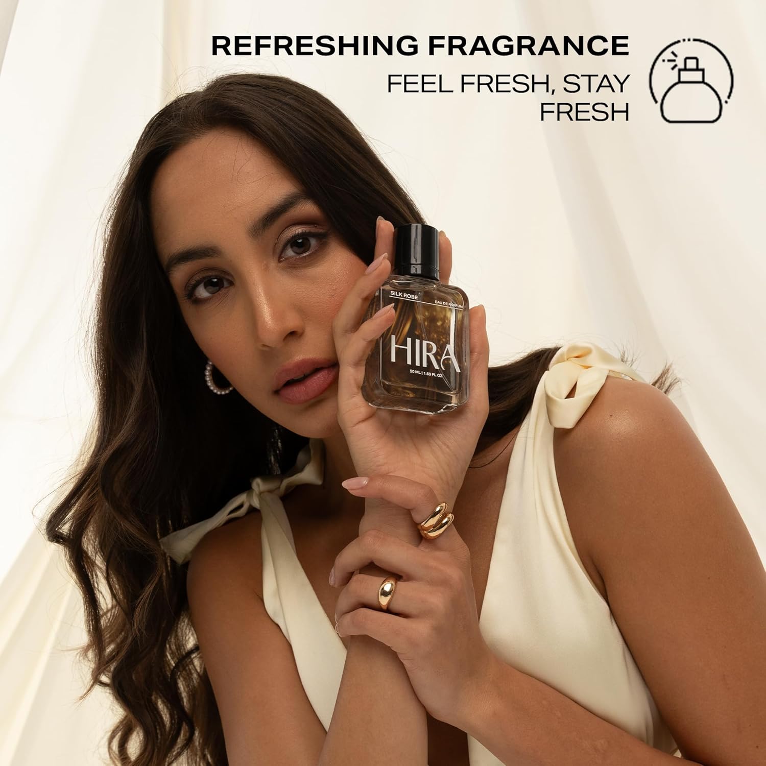 Woman holding a HIRA perfume bottle with text 'Refreshing Fragrance' on a light background