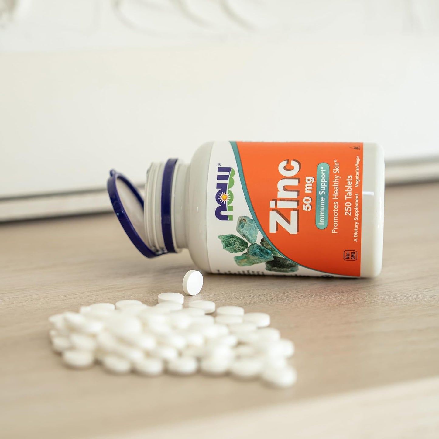 Zinc supplement bottle with scattered tablets on a light surface