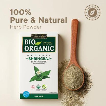 Bio Organic Bhringraj leaf powder packaging with a wooden spoon filled with powder on a beige background.