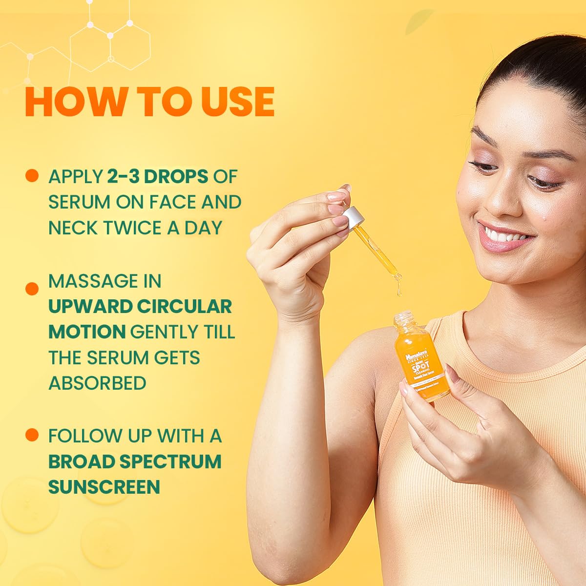 Woman holding a dropper with serum and a bottle on a yellow background, showing how to use skincare serum.