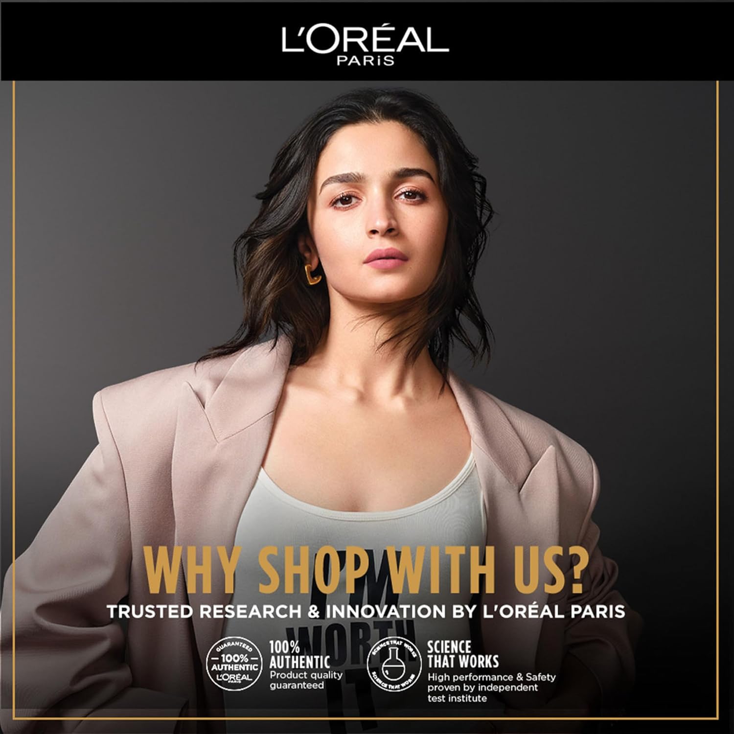 L'Oreal Paris advertisement with a woman in a suit jacket and gray top against a dark background.
