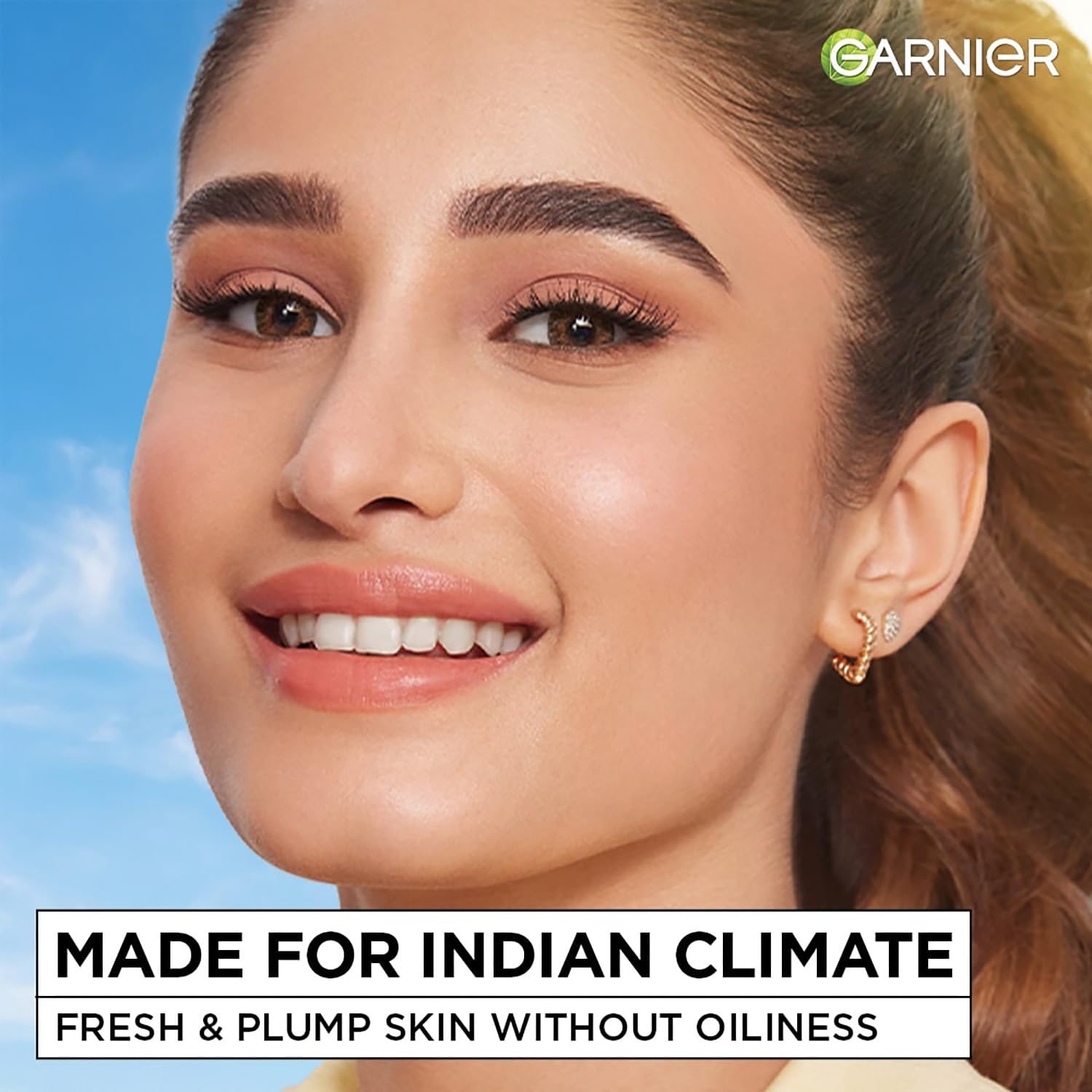 Woman with makeup and earrings against a blue sky, with Garnier branding and text about skin care.