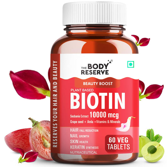 Bottle of The Body Reserve Biotin supplement with red label and white cap, surrounded by red leaves and green leaves.