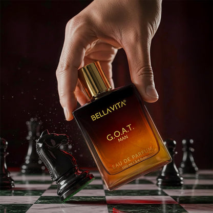 Hand holding a Bellavita G.O.A.T. Man perfume bottle on a chessboard background