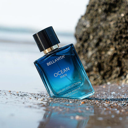 Blue Bellavita Ocean Man perfume bottle on a beach with ocean in the background
