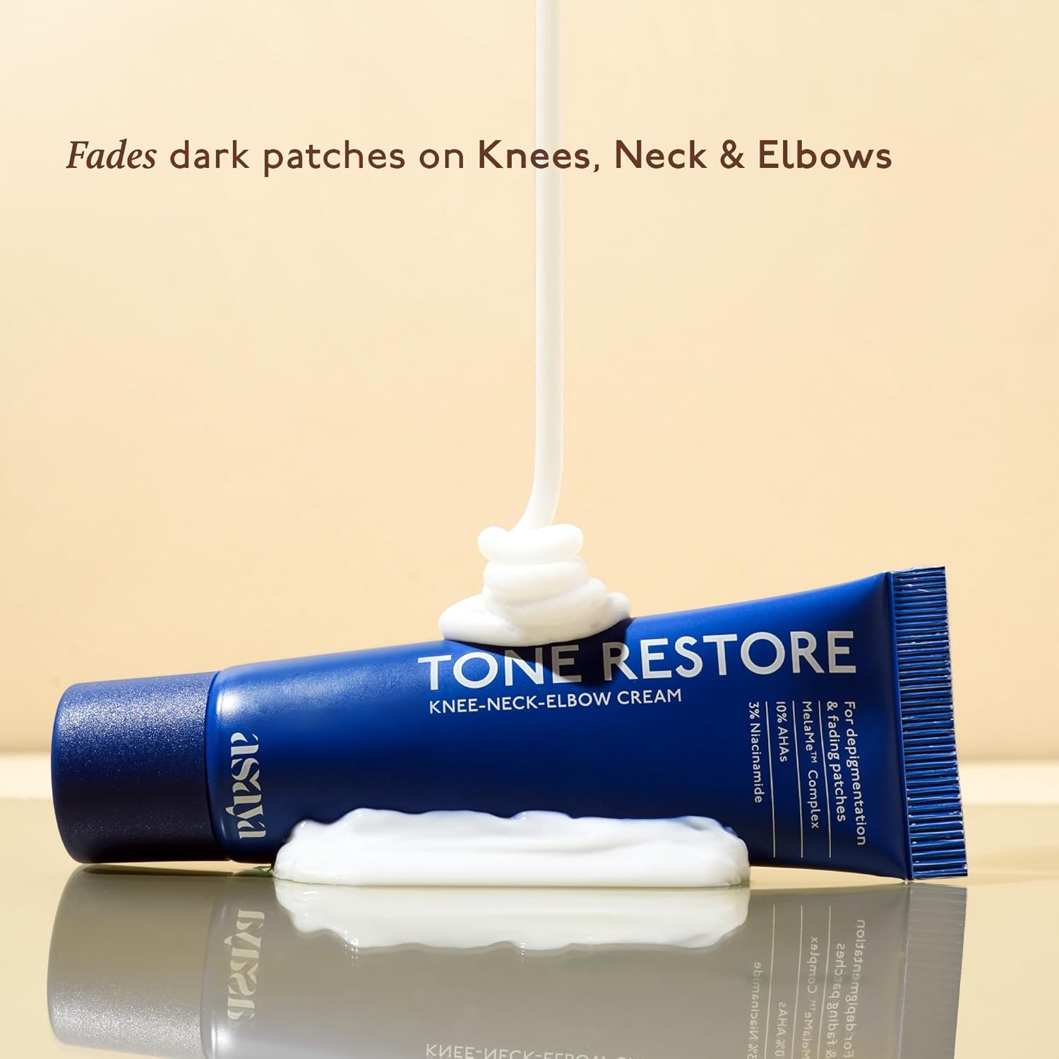 Tube of Tone Restore knee-neck-elbow cream with cream being squeezed out on a beige background