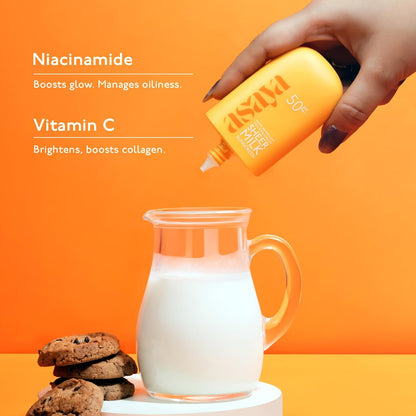 Hand holding a bottle labeled 'asaky' with a glass of milk and cookies on an orange background.