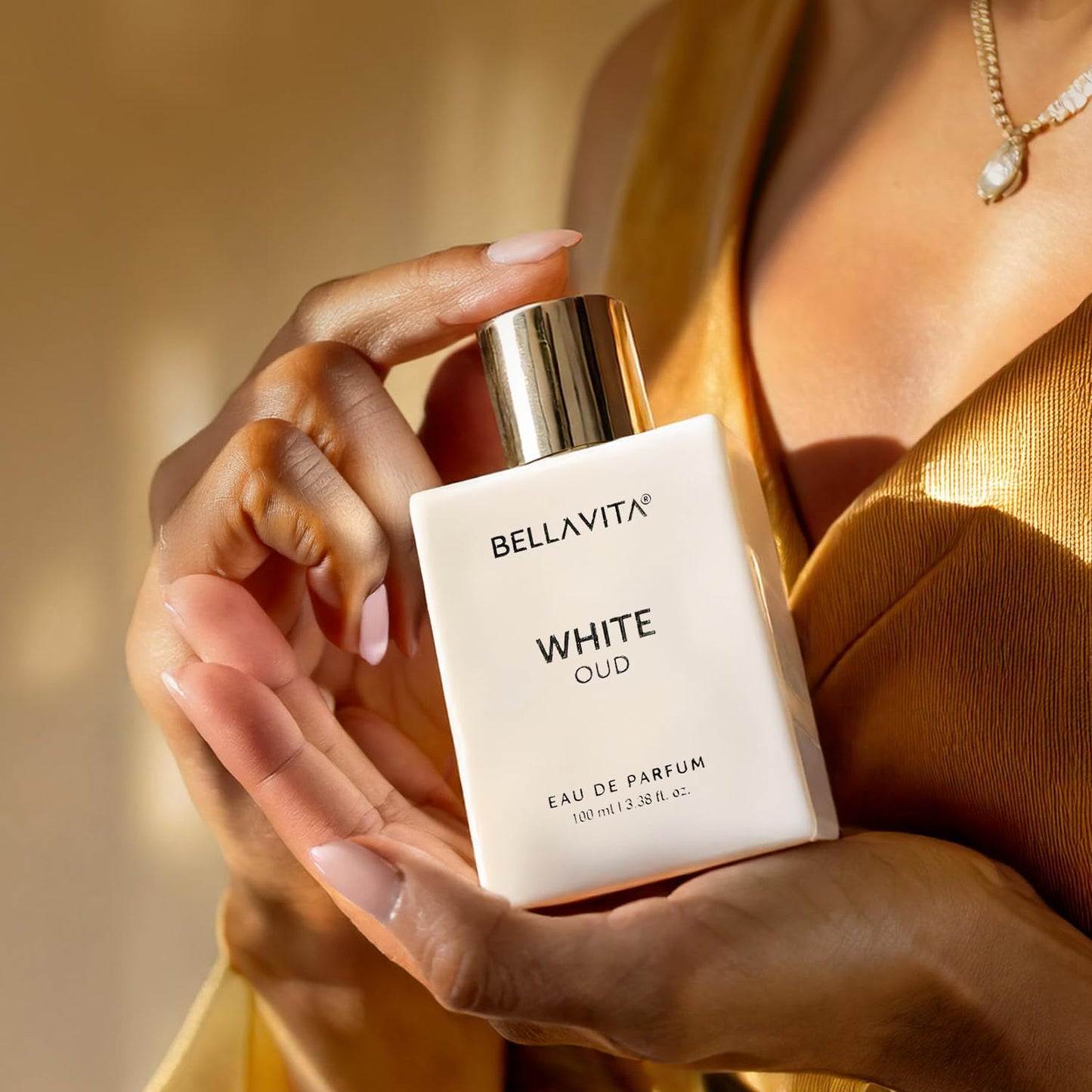 Bottle of Bellavita White Oud Eau de Parfum held by a person in a warm-toned setting