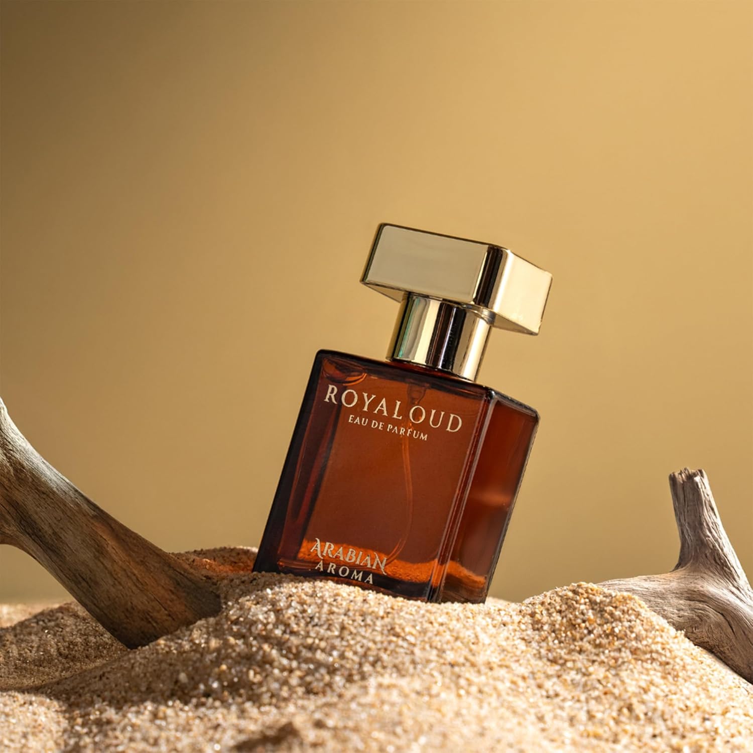 Perfume bottle labeled 'ROYALOUD' on a sandy surface with a warm background