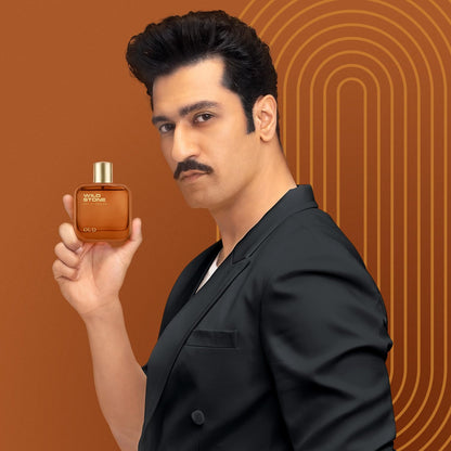 Man holding a brown perfume bottle against an orange background