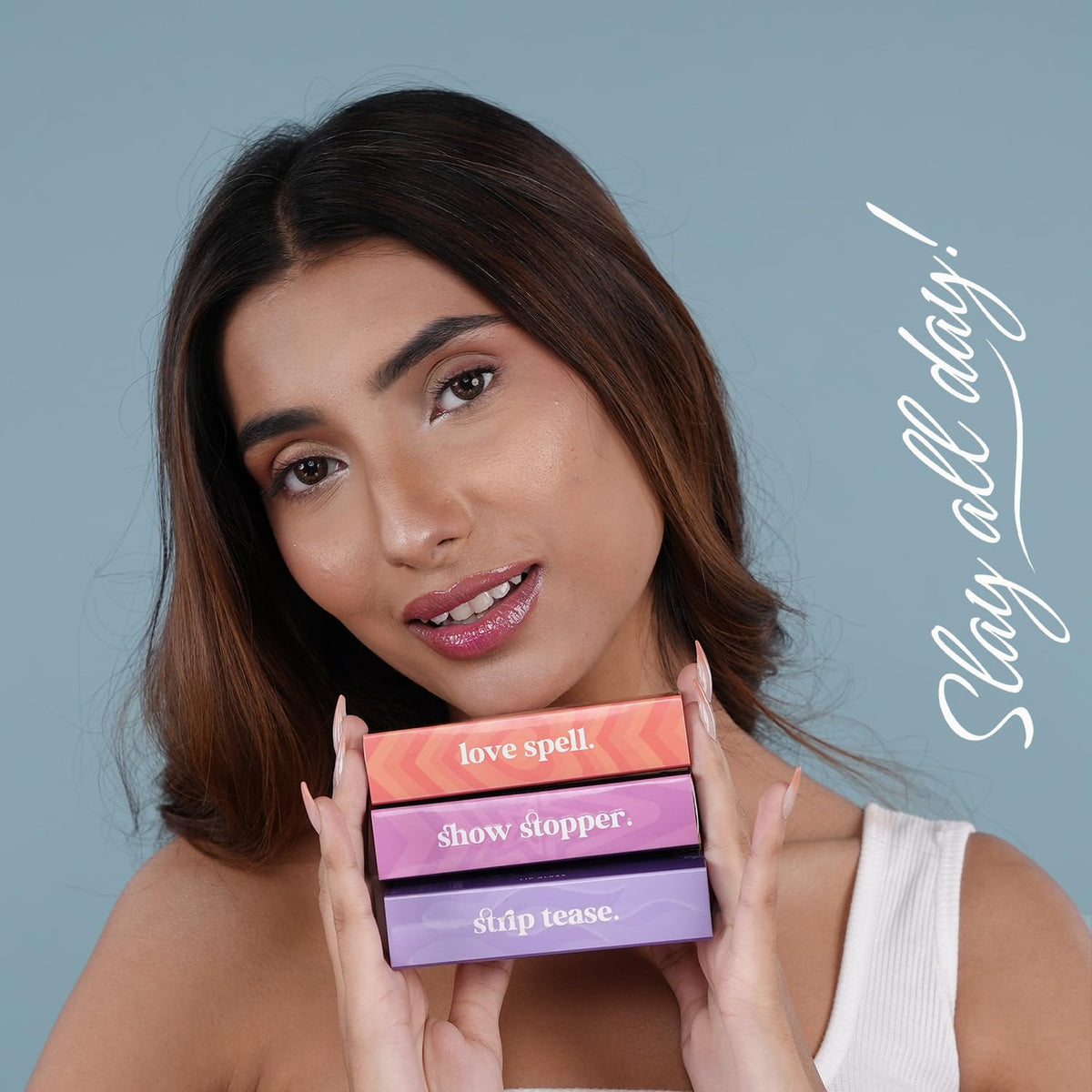 Woman holding makeup products with 'Slay all day!' text on a blue background