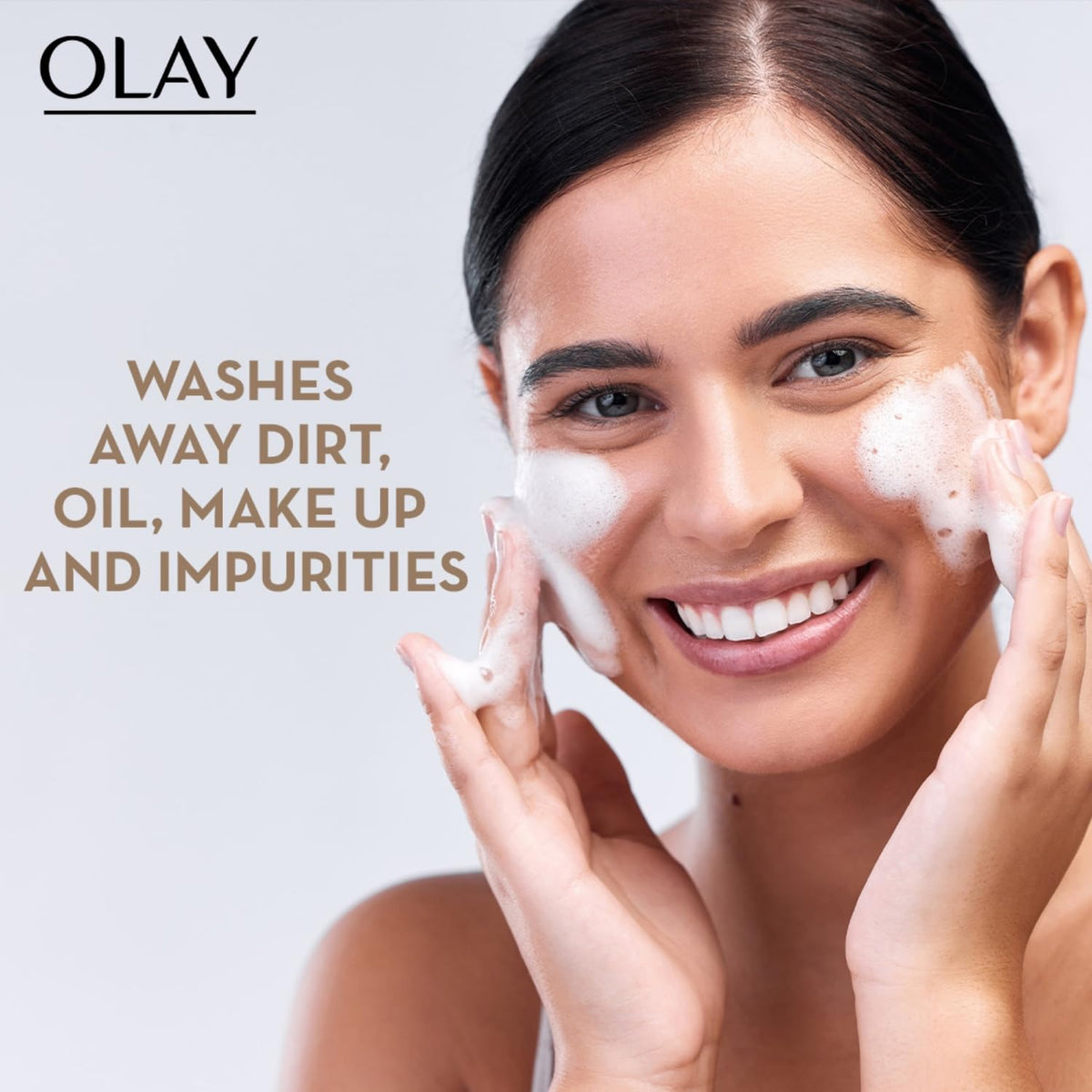 Woman applying Olay facial cleanser with text highlighting product benefits on a light gray background