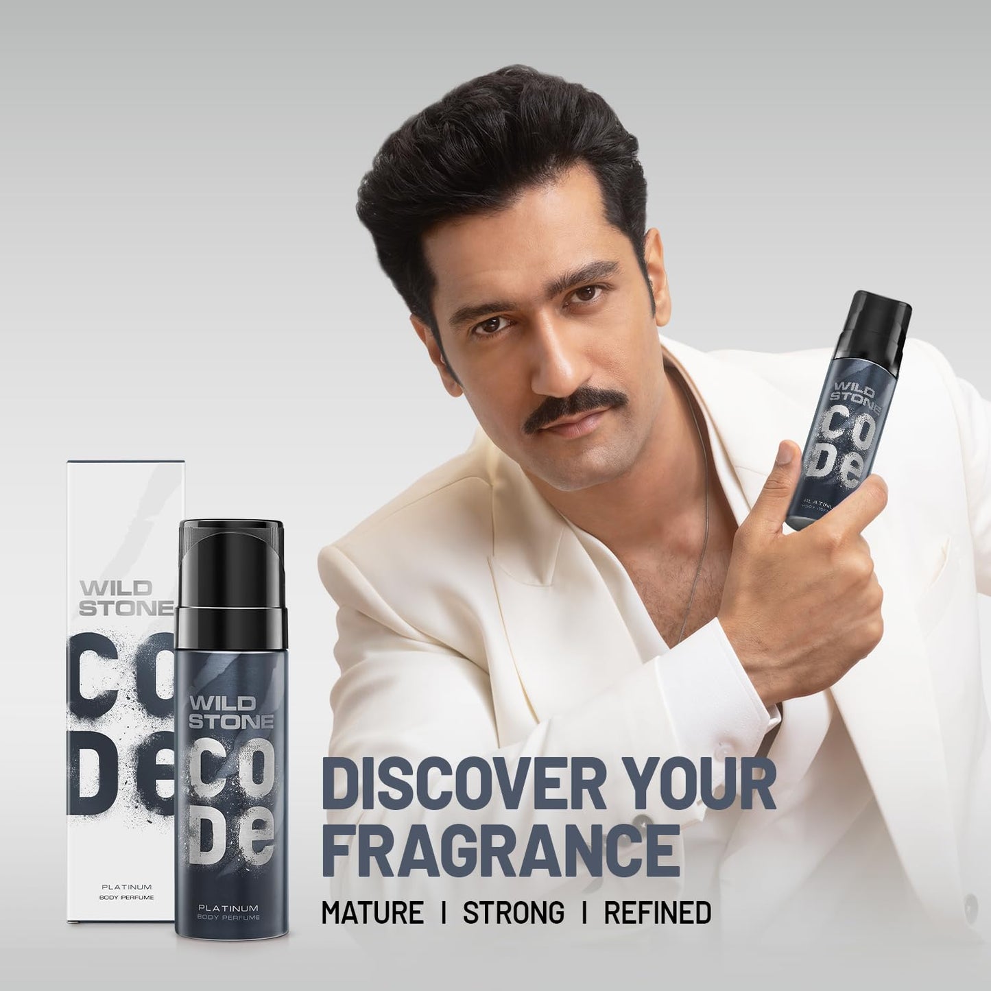 Man holding Wild Stone deodorant with product packaging on a gray background