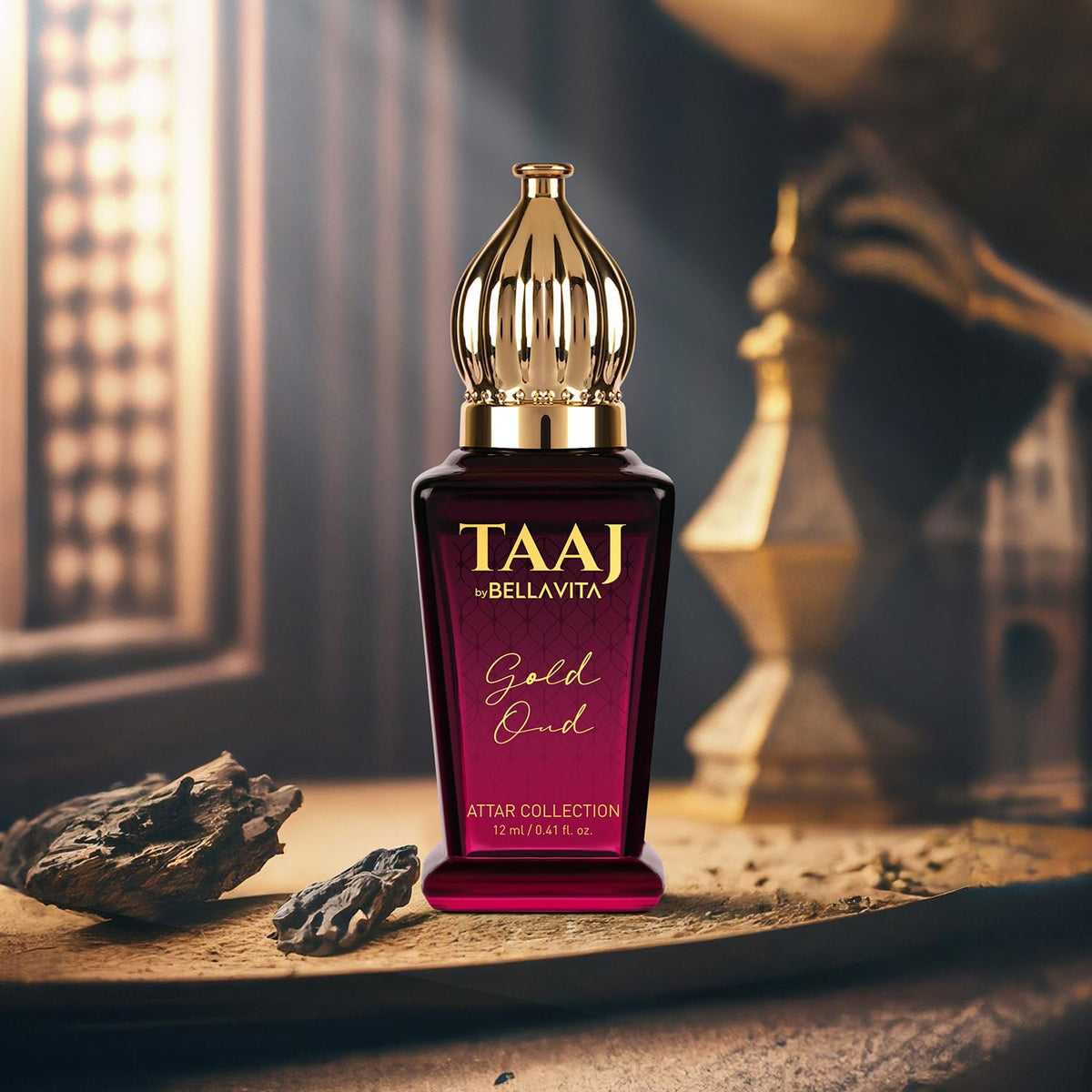 TAAJ Bellavita Gold Oud attar bottle on a wooden surface with a blurred background