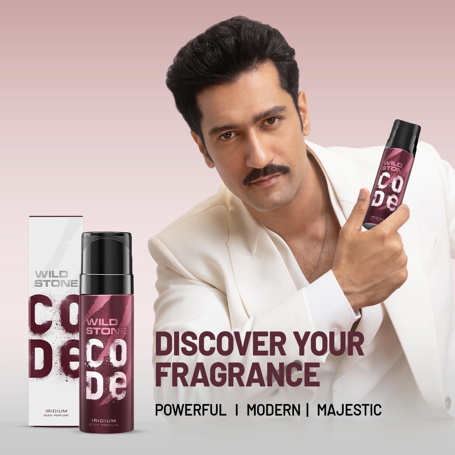 Man holding Wild Stone Code perfume with product packaging on a pink background