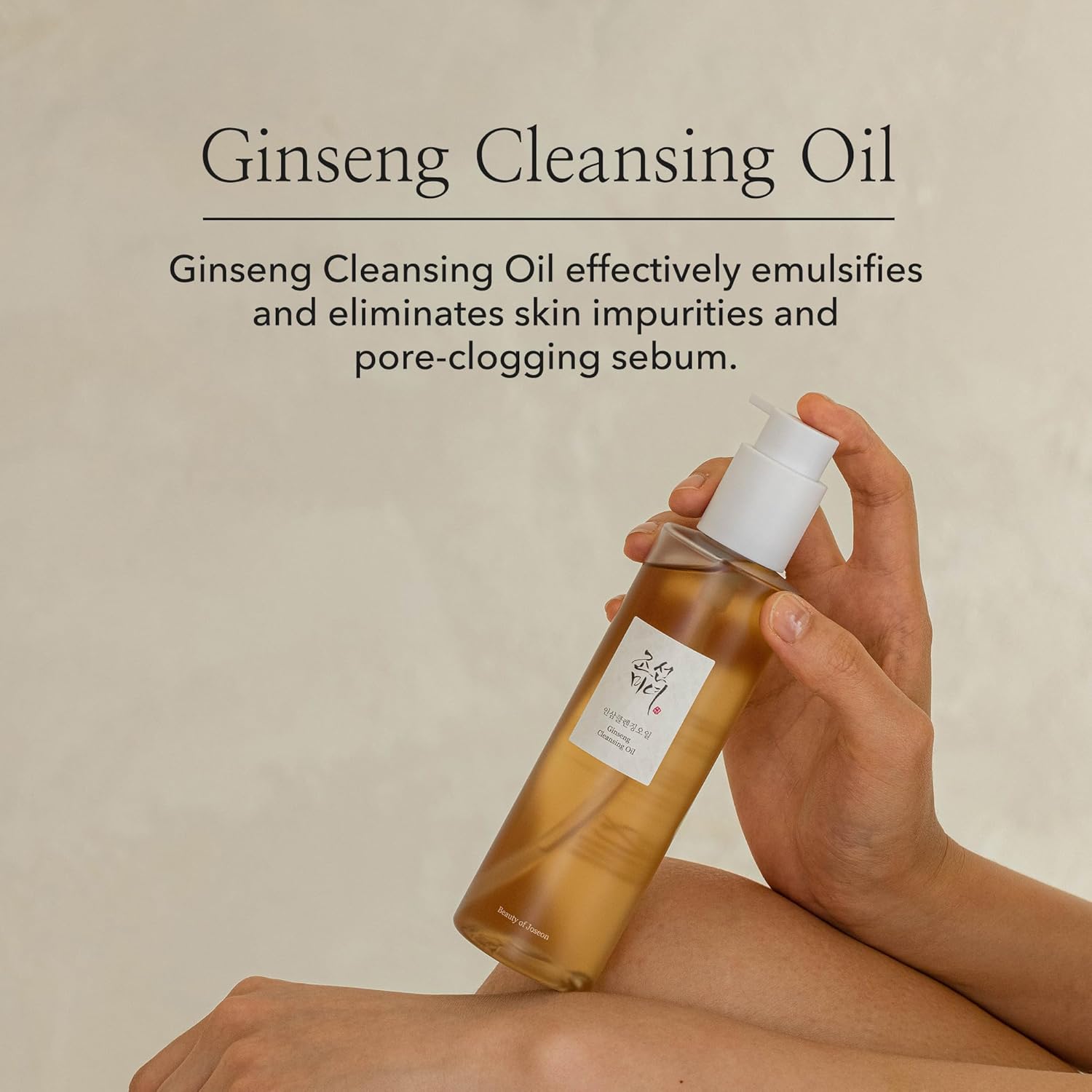 Hand holding a bottle of Ginseng Cleansing Oil with text on a beige background