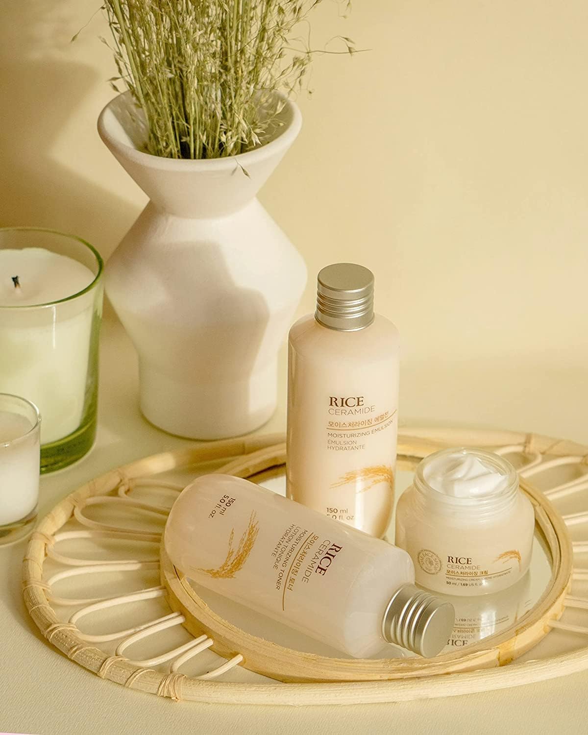 Skincare products on a tray with a candle and plant in the background