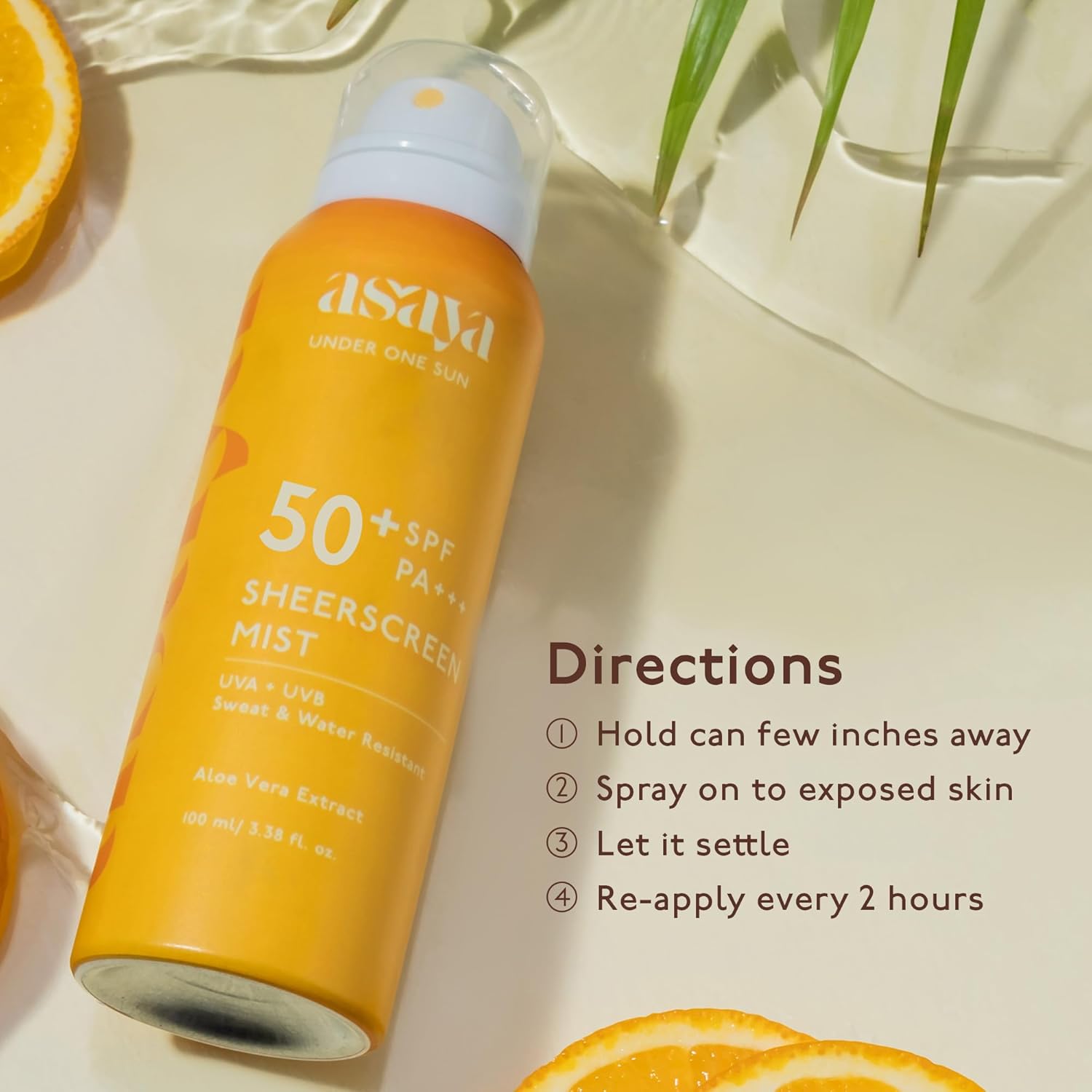 Asaya sunscreen spray bottle with SPF 50+ on a light background with oranges and leaves.