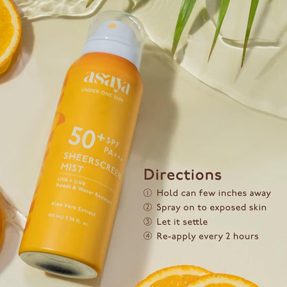 Asaya sunscreen spray bottle with SPF 50+ on a light background with oranges and leaves.