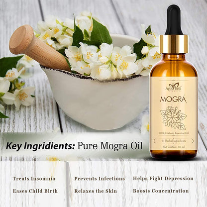 A bottle of Aushpaa Mogra essential oil with a bowl of flowers and a wooden pestle on a wooden surface.