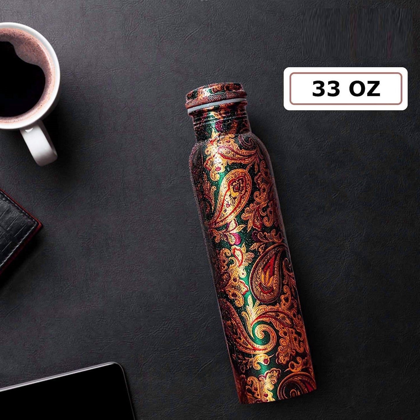 Decorative water bottle with paisley pattern on a dark surface next to a cup of coffee.