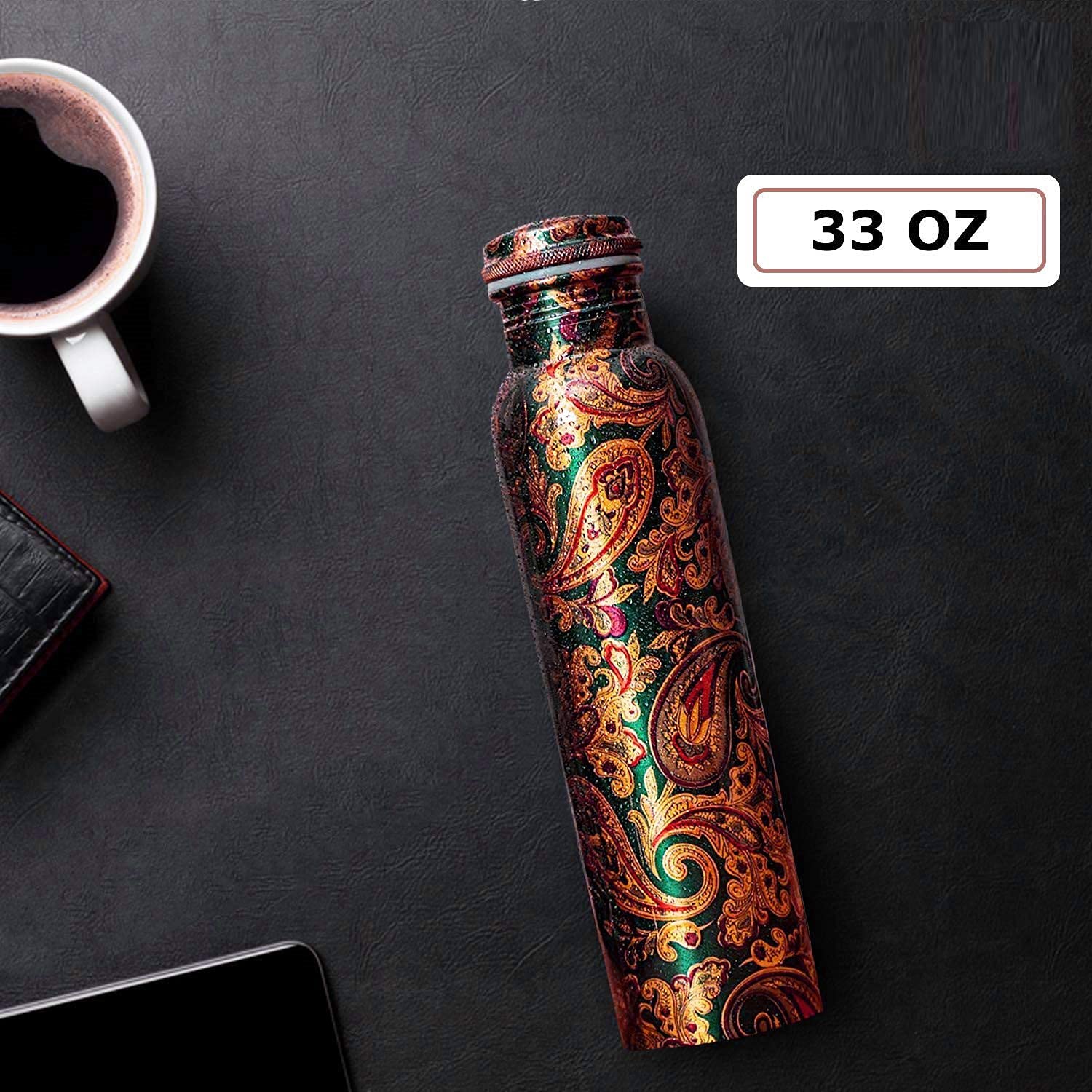 Decorative water bottle with paisley pattern on a dark surface next to a cup of coffee.