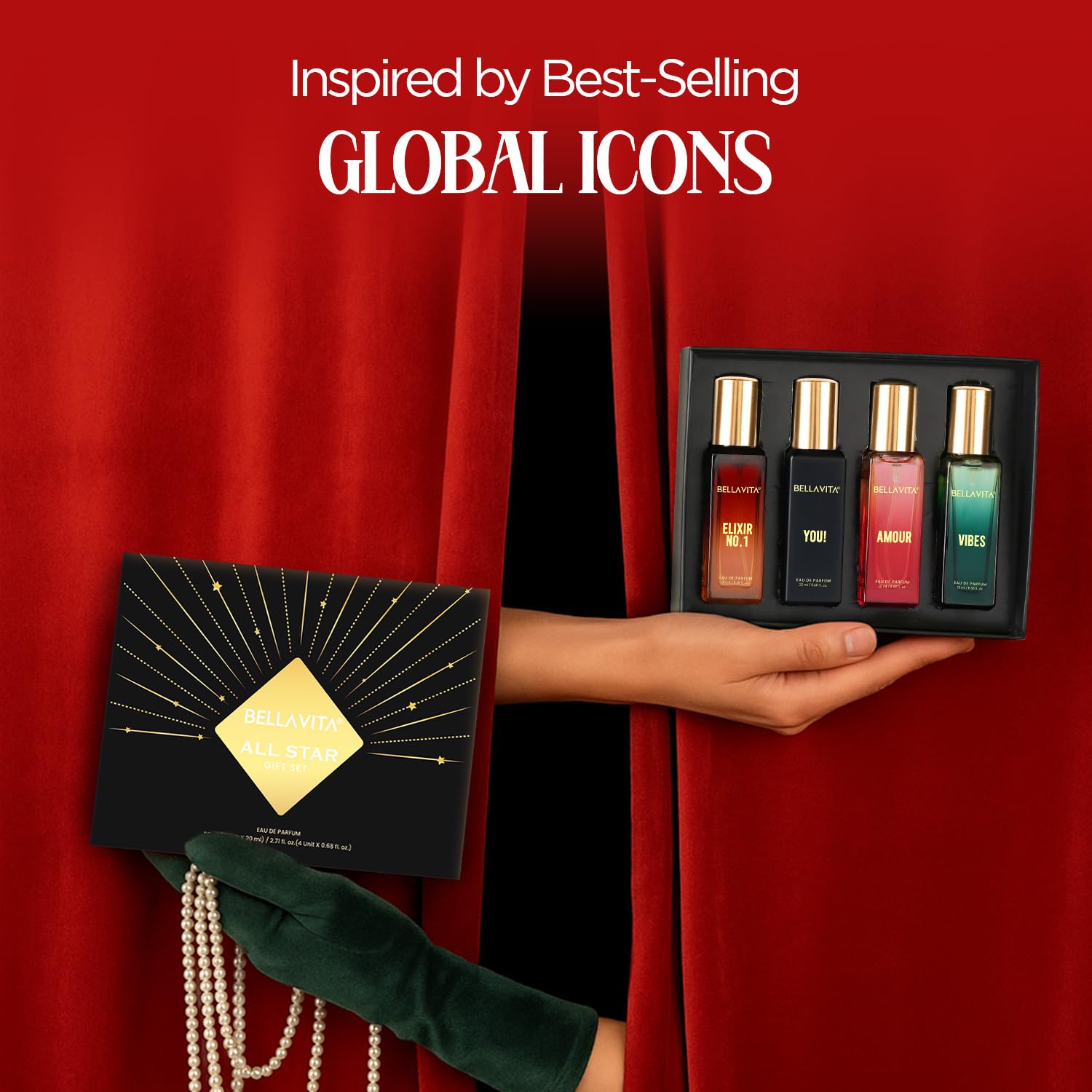 Set of four perfume bottles in a black box held by a hand against a red curtain background.