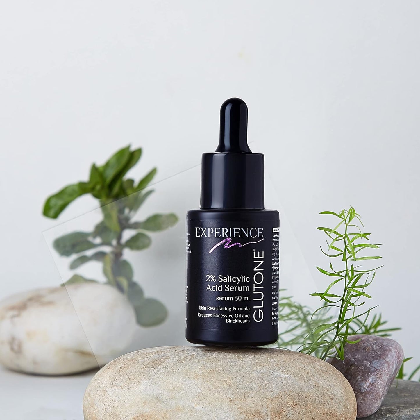 Glutone 2% Salicylic Acid Serum bottle with dropper on a stone surface with plants in the background