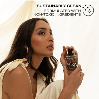 Woman holding a HIRA perfume bottle with 'Sustainably Clean' text on a white background