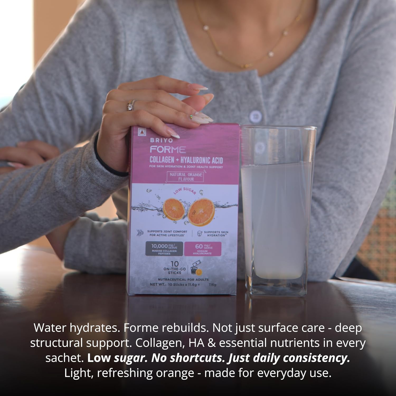 Person holding a box of Bravo Forme Collagen with a glass of water on a table.