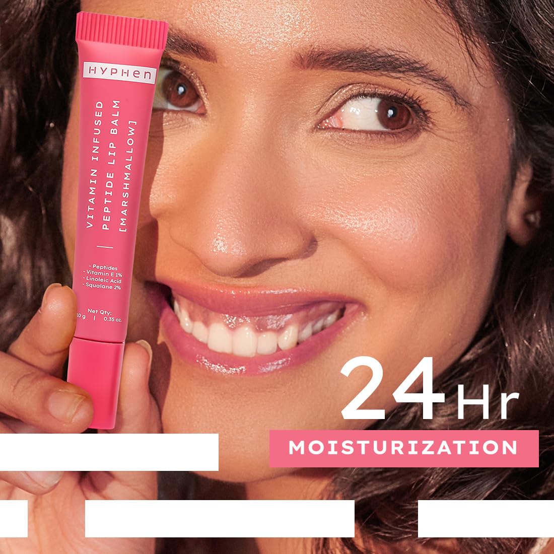 Woman holding a pink lip balm with 'Hyphen' branding, emphasizing 24-hour moisturization.