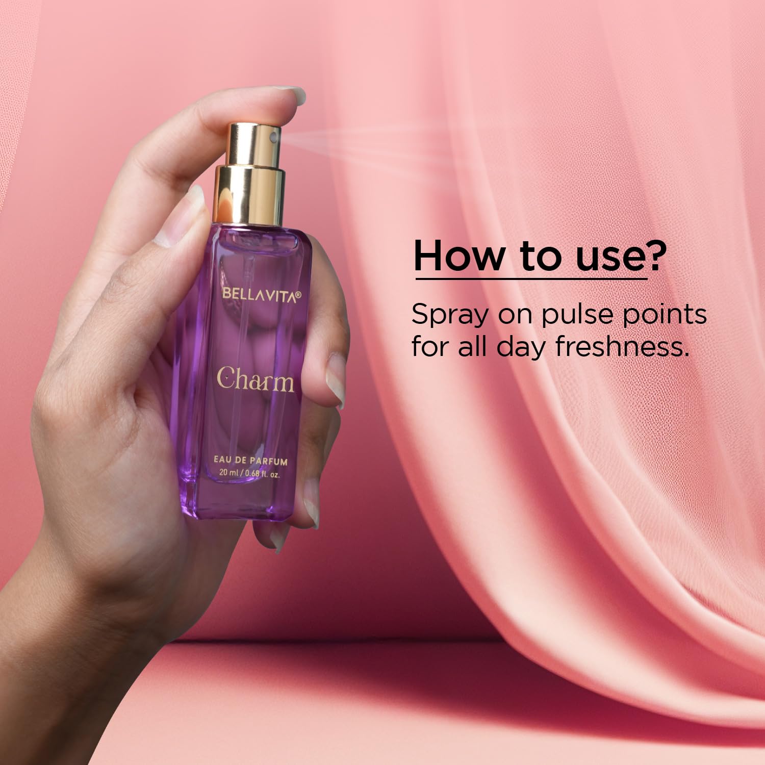 Hand holding a purple Bellavita Charm perfume bottle against a pink background
