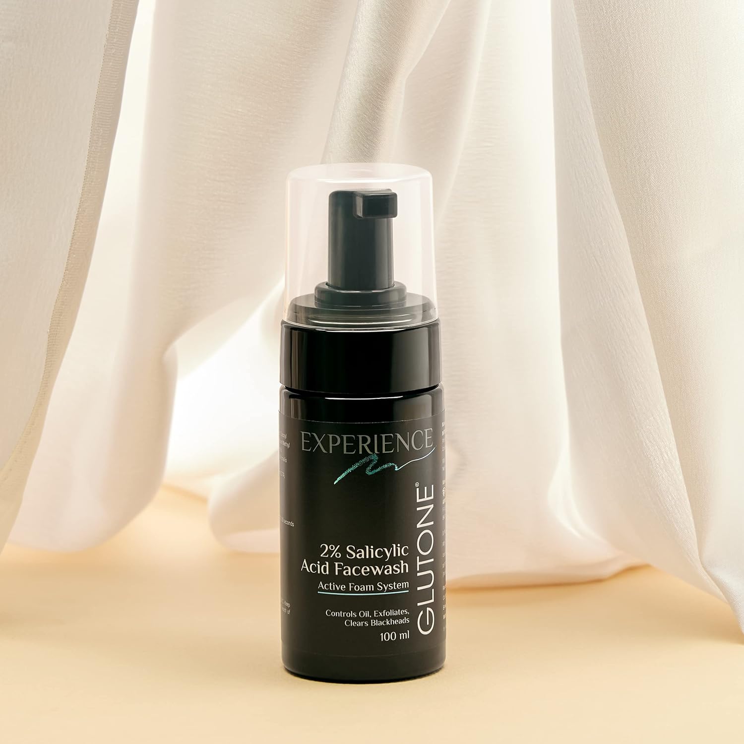 Black skincare bottle with pump on a beige surface and light curtain background