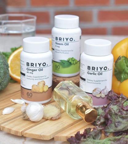 BRIYO oil bottles on a wooden board with fresh ingredients in the background